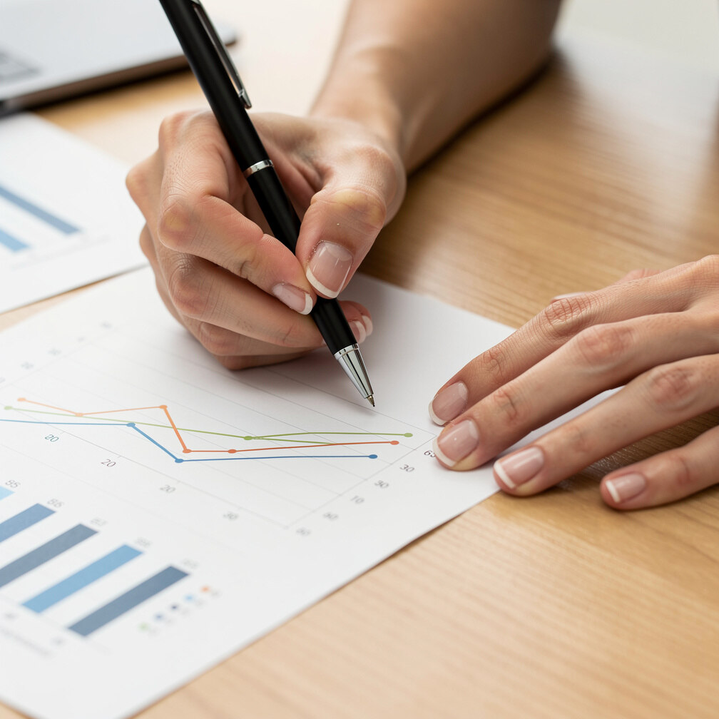 Hands writing on a printed chart with graphs